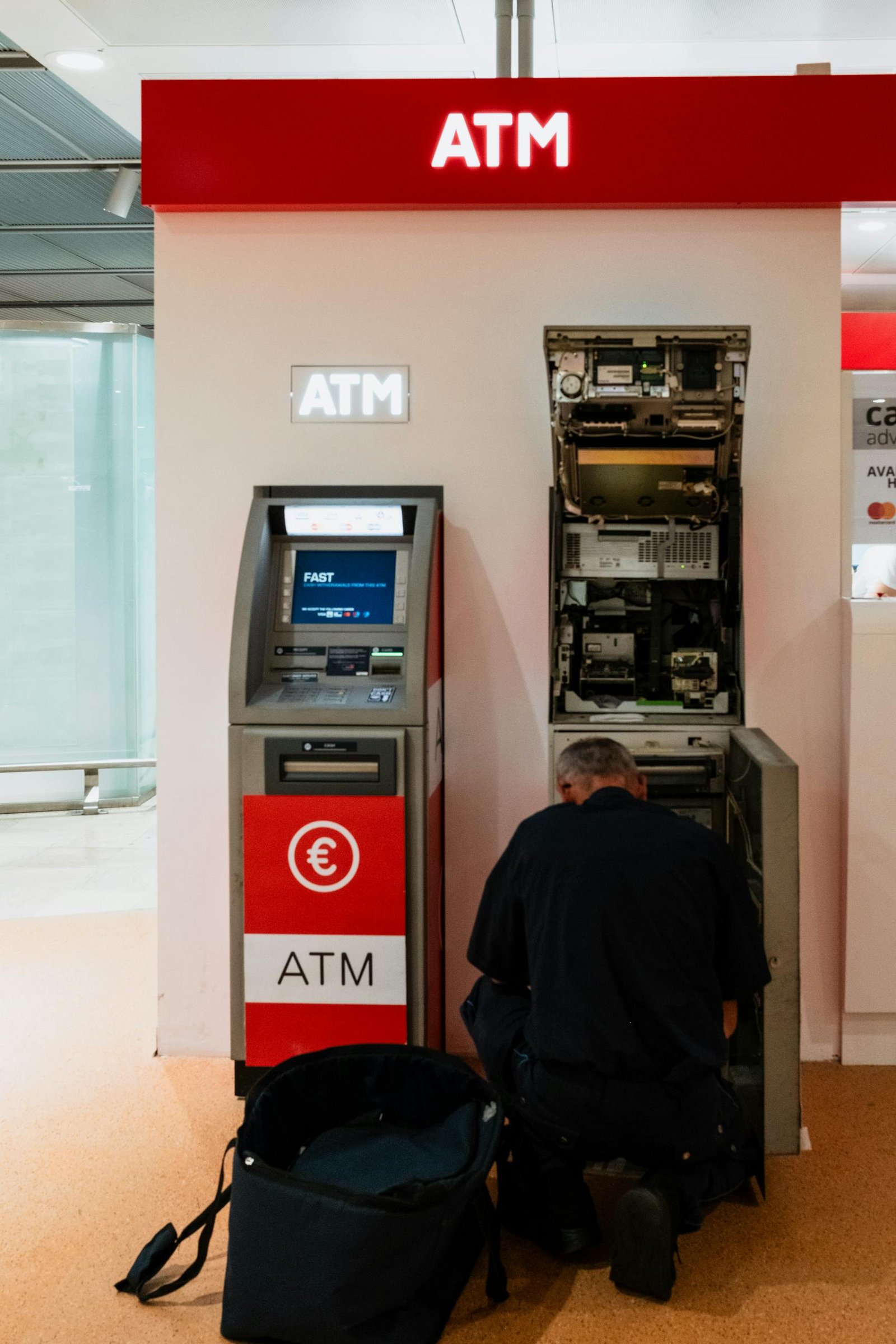 A technician servicing an ATM in a Venice bank lobby. Business and security themes.